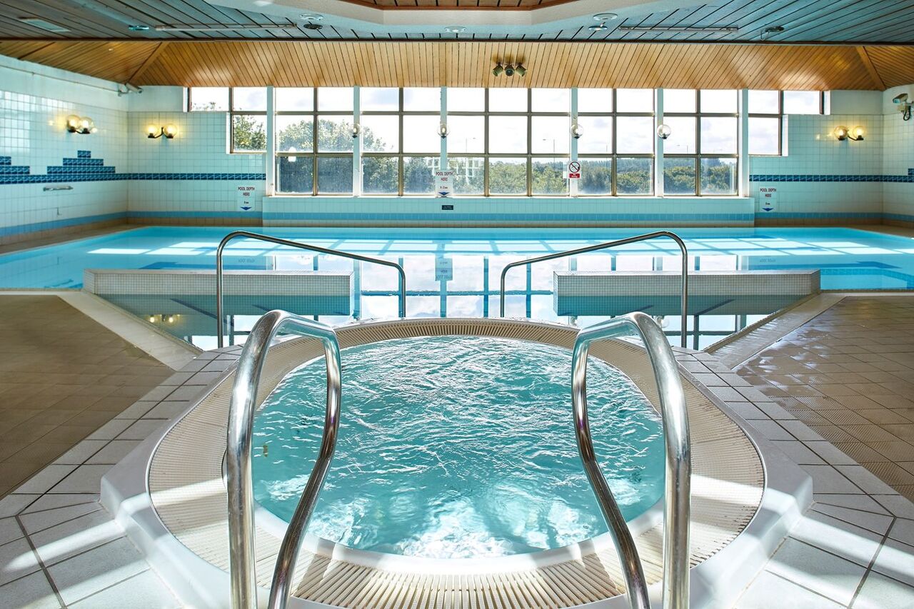 A photo of an empty indoor swimming pool and jacuzzi in a health suite