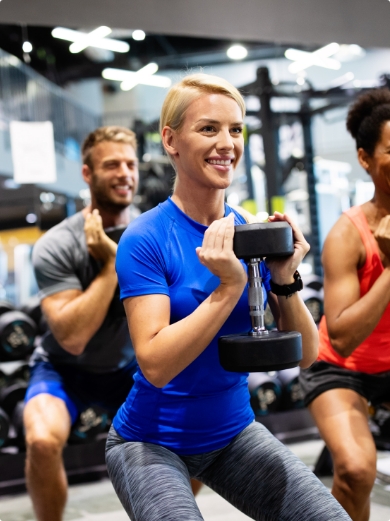 A mixed fitness class with smiling people holding dumbells