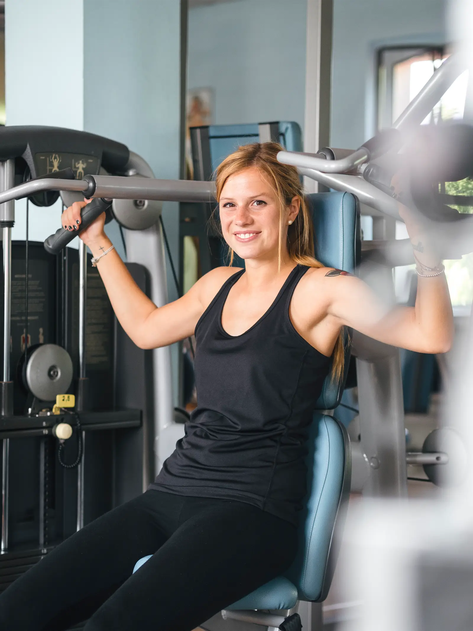 Young blonde woman using weight machine in a well-let gym