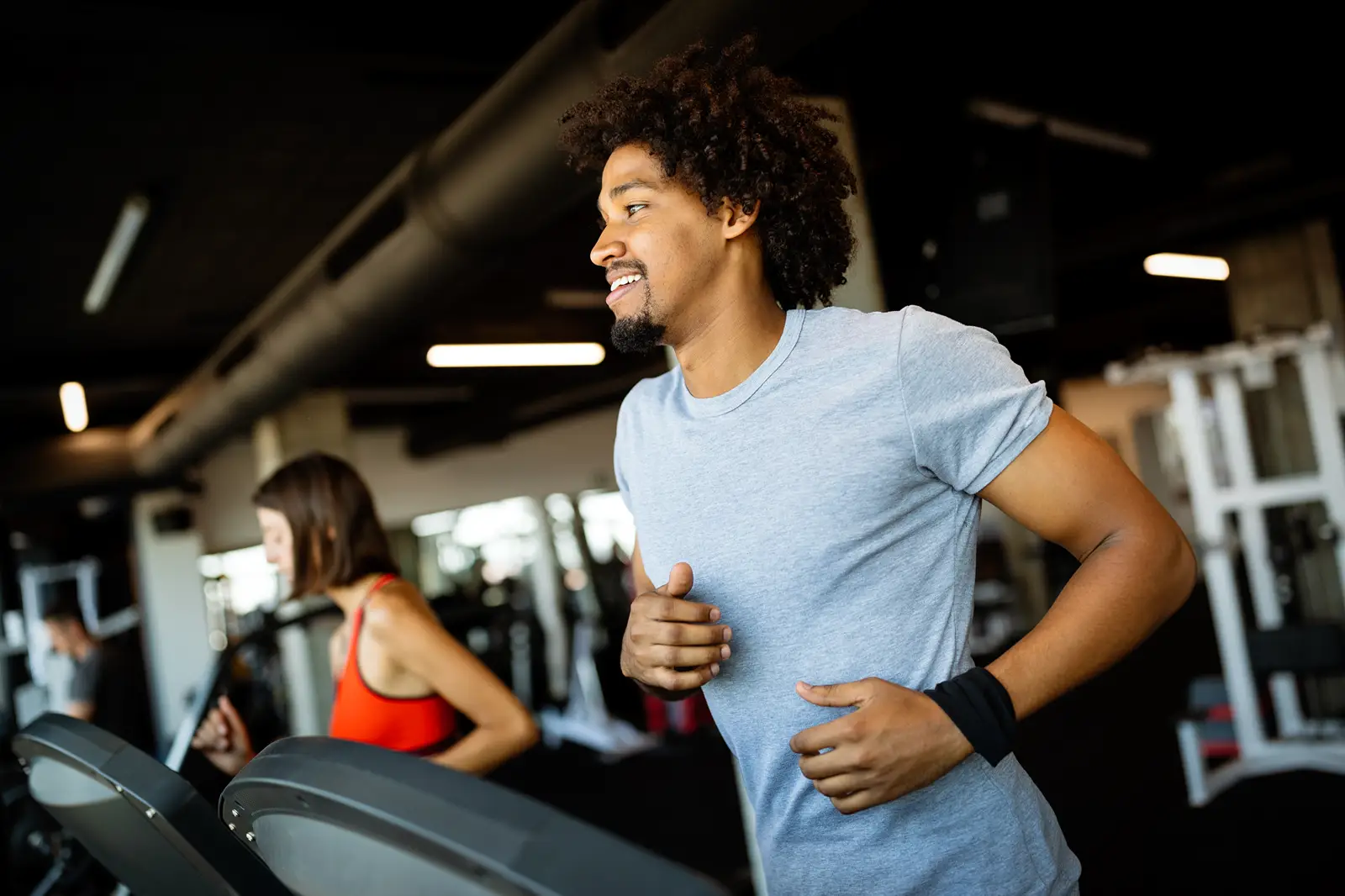 A happy black man using a treadmill in a gym