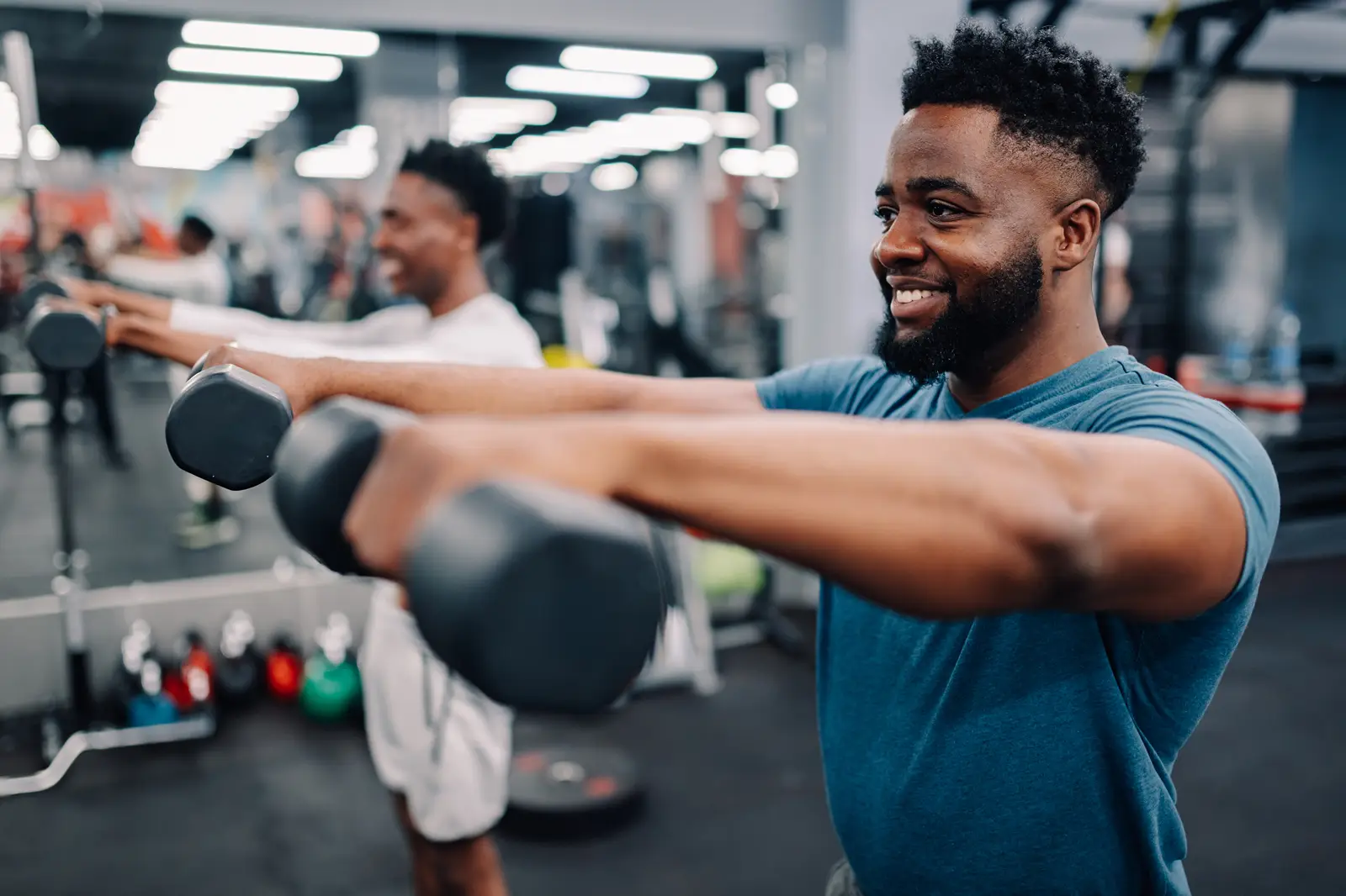 Two men in a gym fitness class lifting dumbells